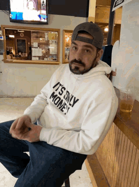 a man wearing a white sweatshirt that says it 's only money