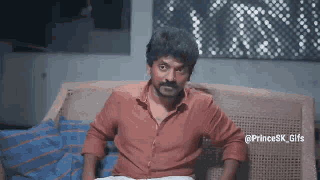 a man with a mustache is sitting on a wicker couch .