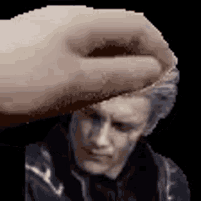 a hand is holding a man 's head in front of a black background .