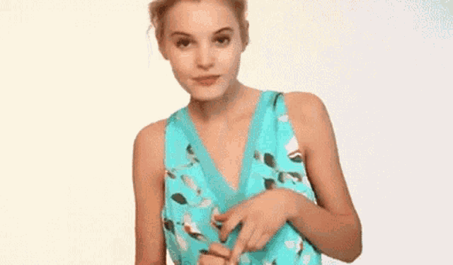 a woman in a blue dress is holding her hands together in front of her face .