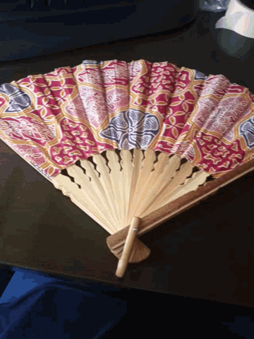 a wooden fan with a red and blue pattern on it