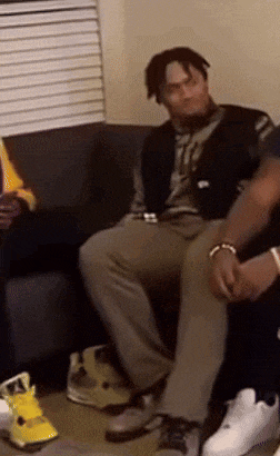 a group of people are sitting on a couch and one of them is wearing a vest that says ' nike ' on it