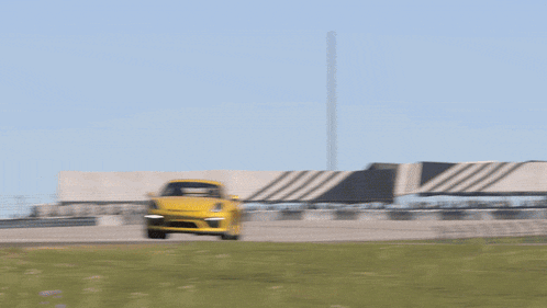 a yellow sports car is driving on a race track under a sign that says " tuvrheinland "