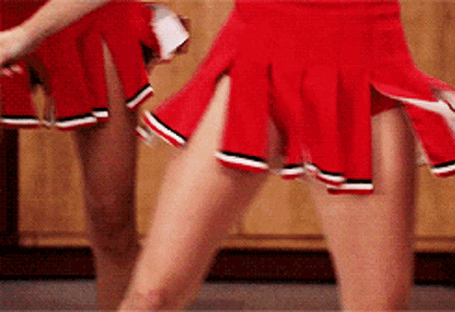 two cheerleaders wearing red skirts with black stripes