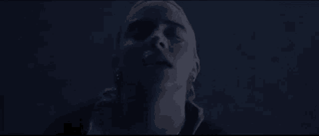 a close up of a woman 's face in the dark with her eyes closed .