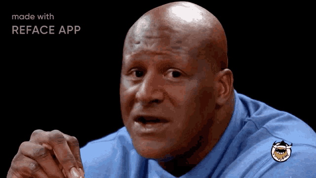 a bald man wearing a blue shirt with a shark on it