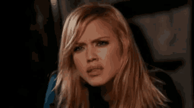 a woman with long blonde hair is making a funny face and looking at the camera .