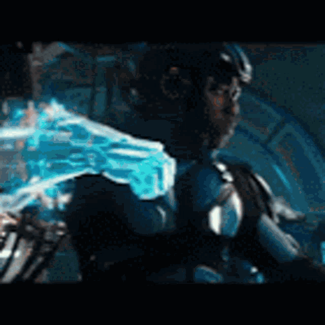 a man in a futuristic suit is holding a blue object in his hand
