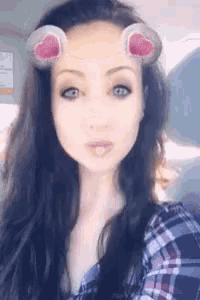 a woman with long black hair is wearing a snapchat filter with ears on her face .