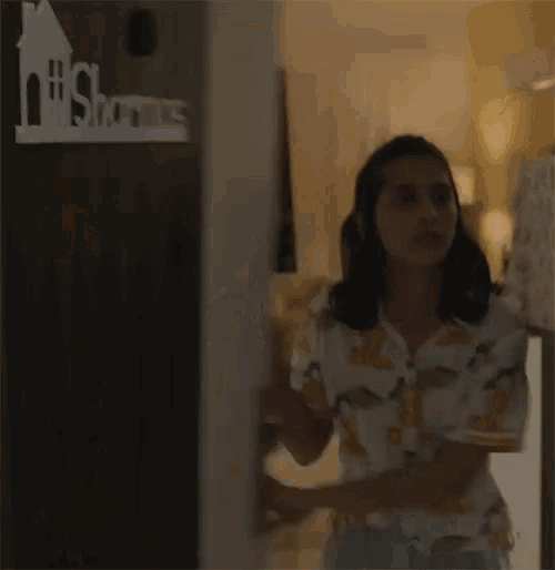 a woman is standing in a living room wearing a shirt with a cartoon character on it .