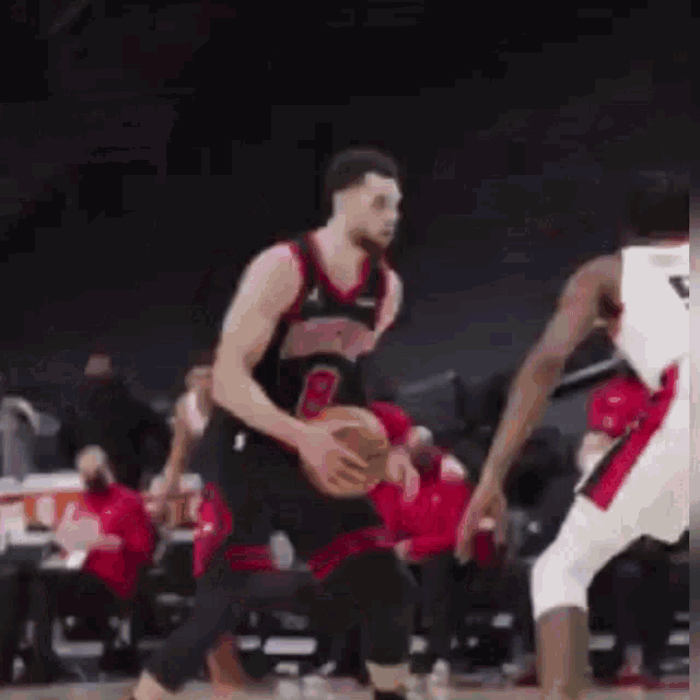 a basketball player is dribbling a ball while another player tries to block him .