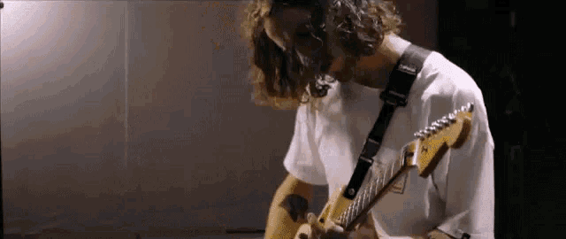 a man with long curly hair is playing an electric guitar in a recording studio .