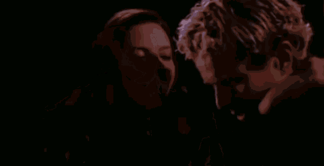 a man and a woman are standing next to each other in a dark room .