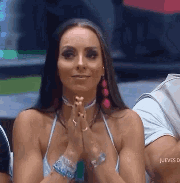a woman in a blue tank top is clapping her hands together
