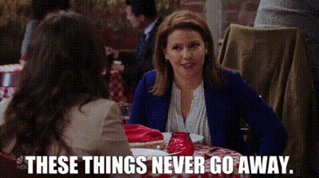 a woman is sitting at a table in a restaurant with the words `` these things never go away '' .
