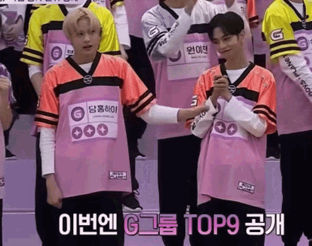 a group of young men wearing pink and orange jerseys are standing next to each other in front of a crowd .