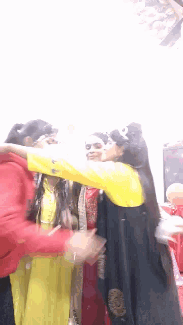 a group of women are hugging each other in a room with balloons in the background