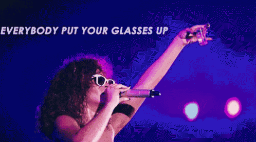 a woman singing into a microphone with the words everybody put your glasses up