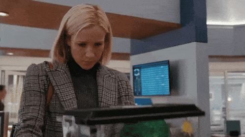 a woman in a plaid jacket is looking at a small aquarium