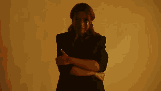 a woman with her arms crossed is wearing a black jacket