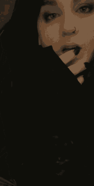 a close up of a woman 's face with a black nail