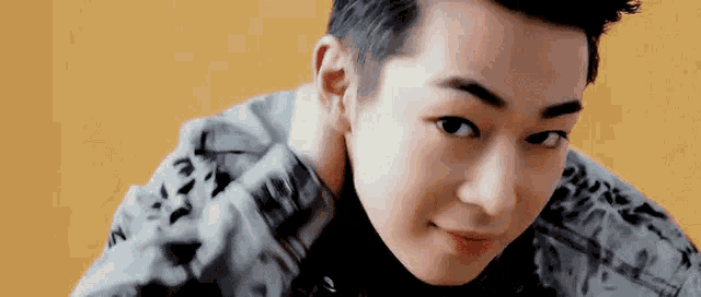 a close up of a young man 's face with his hand on his neck and a yellow background .
