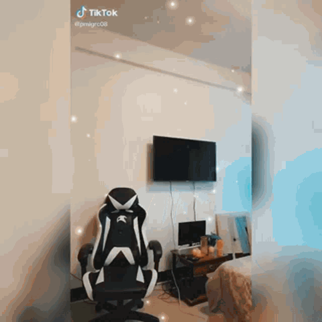 a black and white gaming chair is sitting in a living room next to a television .