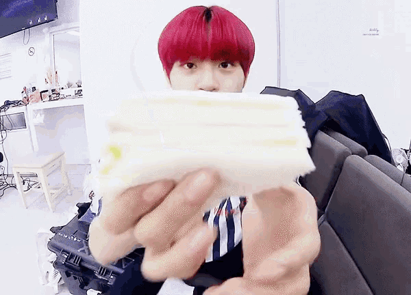 a person with red hair is holding a piece of bread in front of their face