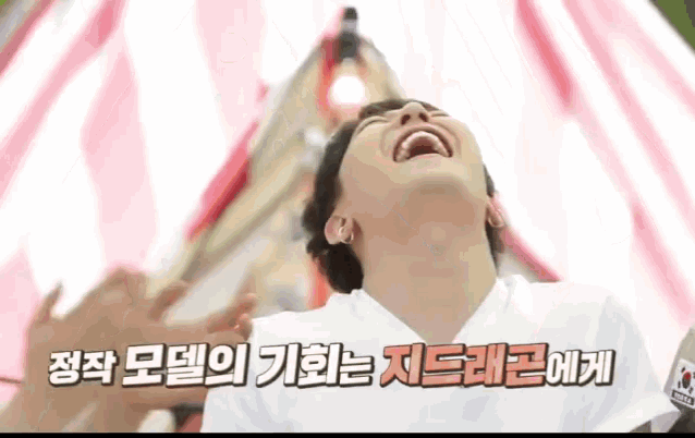 a man in a white shirt is laughing in front of a red and white tent .