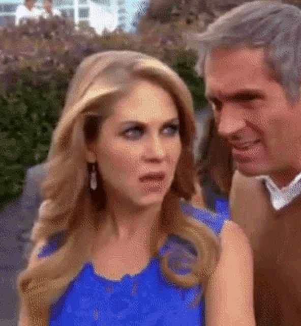 a man and a woman are standing next to each other and the woman is wearing a blue top