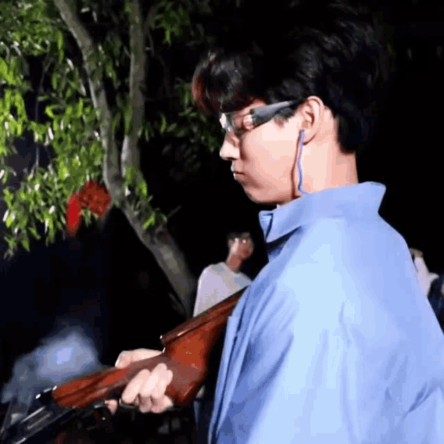 a man in a blue shirt is holding a shotgun in his hands .
