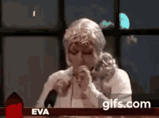a woman in a wig is sitting at a table with a microphone .