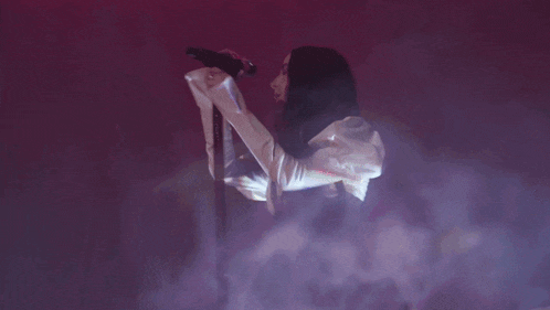 a person in a white shirt is singing into a microphone in a dark room