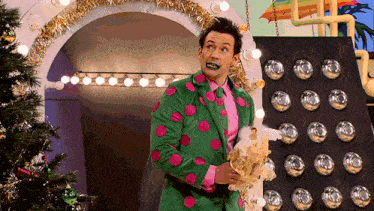 a man in a green and pink polka dot suit holds something