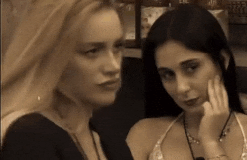 two women are looking at each other and one has her hand on her chin