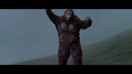 a giant gorilla is standing on top of a hill with its arms in the air