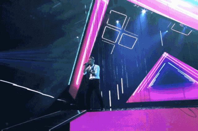 a man singing into a microphone on stage