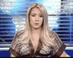 a blonde woman is standing in front of a blue screen .