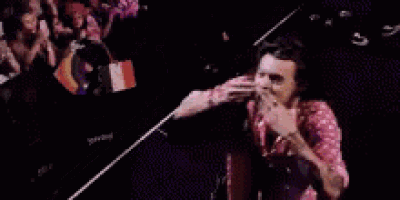a man in a pink shirt is dancing on a stage in front of a crowd of people .