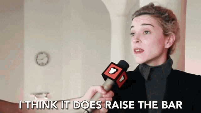 a woman is talking into a microphone and says i think it does raise the bar .