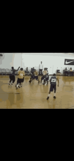 a basketball game is being played on a court with a nike logo on the wall .