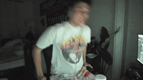 a man wearing a trump shirt is dancing in front of a computer