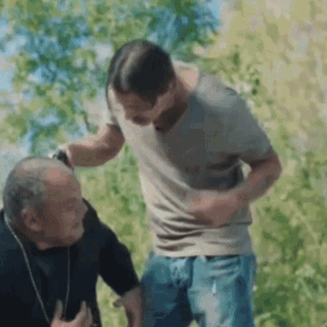 two men are standing next to each other in a field and one of them is holding the other 's arm .
