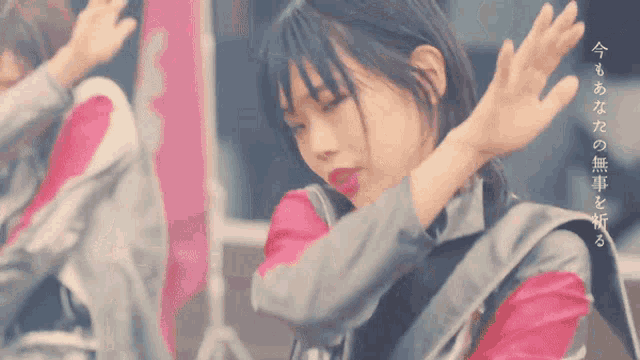 a girl in a pink and grey outfit is dancing with her arms outstretched