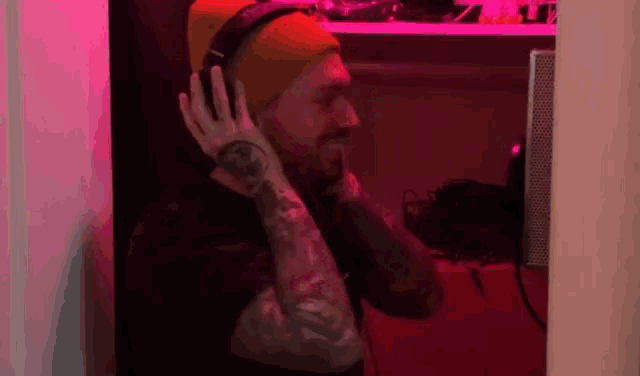 a man wearing headphones and a beanie has a tattoo on his arm