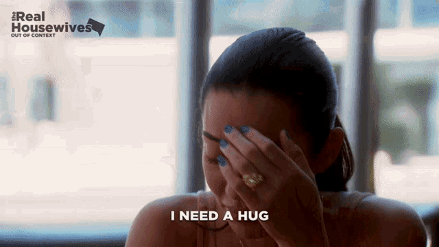 a woman covering her face with her hand and the words i need a hug
