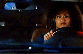 a woman is driving a car at night and looking at the rear view mirror .