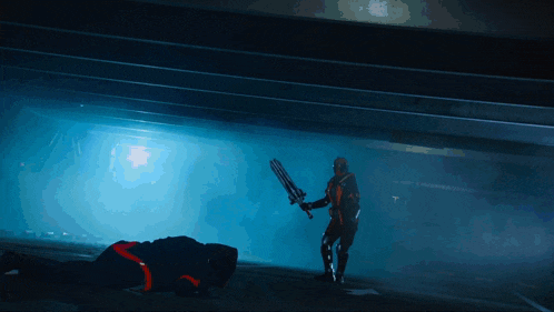 a man holding a sword is standing next to another man who is laying on the ground