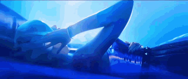 a woman with blue hair is laying down in a blue room holding a bottle of water .