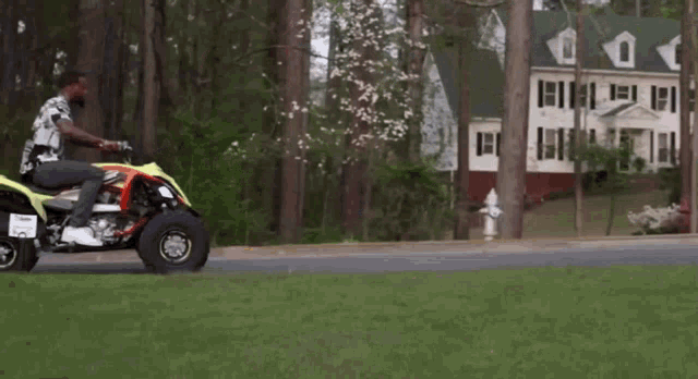 a man is doing a trick on a four wheeler in front of a house